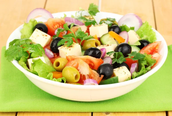 Salade fraîche dans une assiette sur une table en bois — Photo