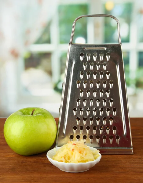 Metal grater and apple, on bright background — Stock Photo, Image