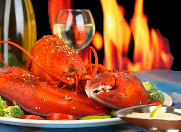 Красный лобстер на блюдечке на деревянном столе на огненном фоне — стоковое фото