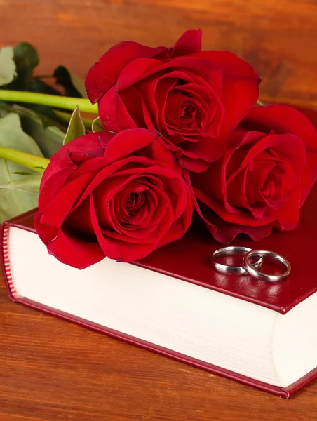 Обручальные кольца на библии с розами на деревянном фоне — стоковое фото