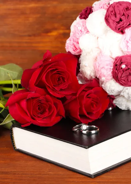 Anillos de boda en la biblia con rosas sobre fondo de madera — Foto de Stock