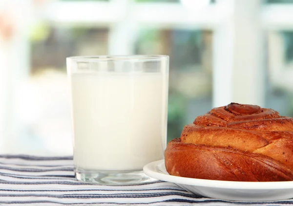 Rollo de pan y vaso de leche sobre fondo de ventana — Foto de Stock
