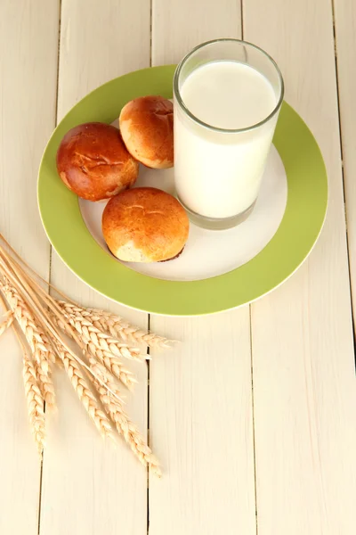 Panecillos y vaso de leche sobre mesa de madera — Foto de Stock