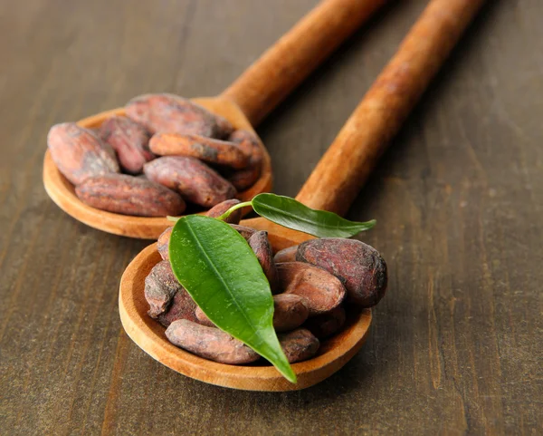 木製の背景にスプーンで葉のココア豆 — ストック写真