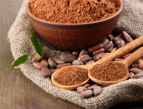 Kakaový prášek a kakaových bobů na dřevěné pozadí — Stock fotografie