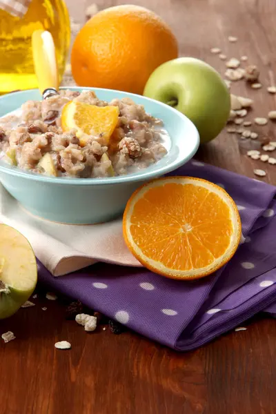 Harina de avena útil en un tazón con fruta en una mesa de madera — Foto de Stock