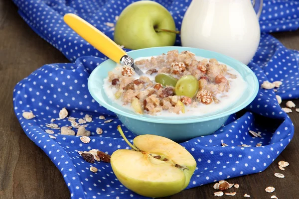 Useful oatmeal in bowl with fruit on wooden table close-up — Stock Photo, Image