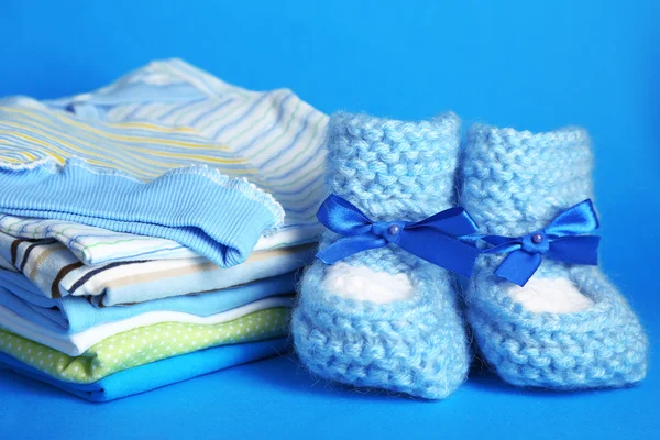 Pile of baby clothes on blue background — Stock Photo, Image