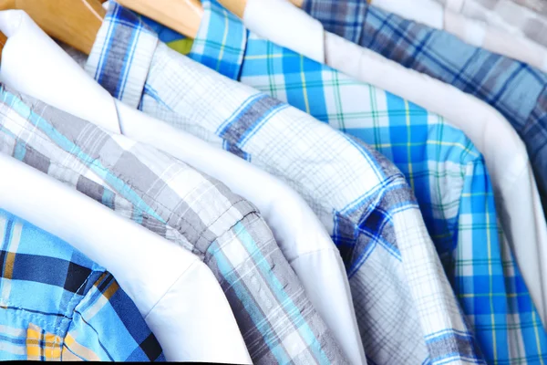 Men's shirts on hangers on wooden background