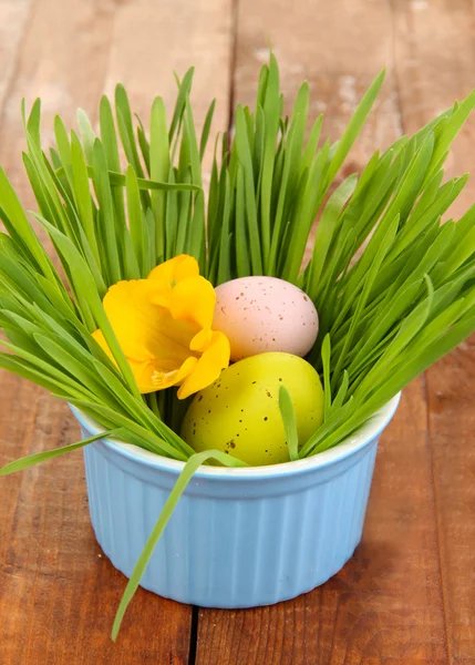 Påskägg i skål med gräs på träbord närbild — Stockfoto