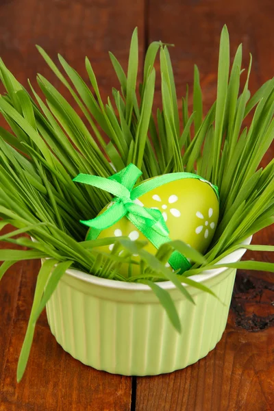 Easter eggs in bowl with grass on wooden table close up — Stock Photo, Image
