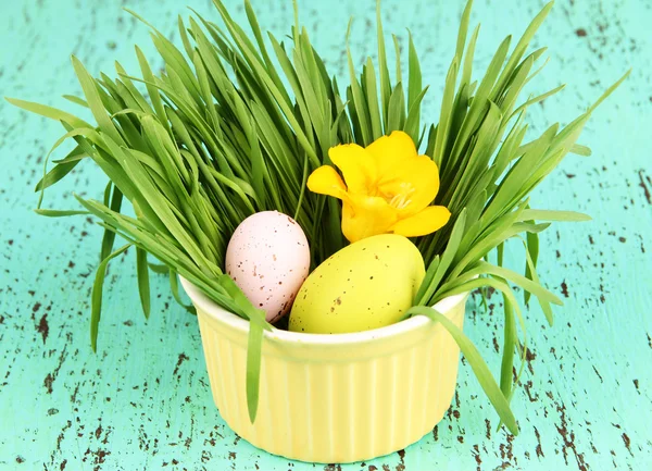 Uova di Pasqua in ciotola con erba su tavolo di legno verde da vicino — Foto Stock