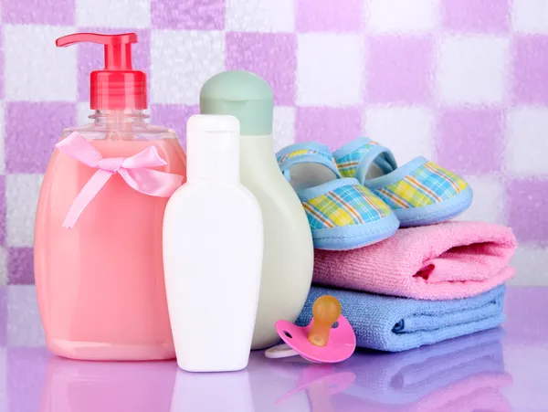 Baby cosmetics and towels in bathroom on violet tile wall background — Stock Photo, Image