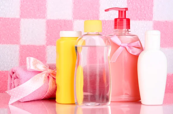 婴儿化妆品和在粉红色瓷砖墙背景上浴室毛巾 — 图库照片