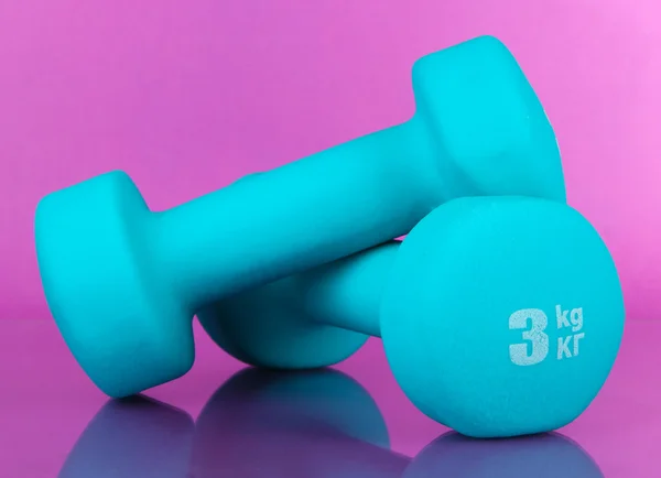 Dumbbells on purple background — Stock Photo, Image