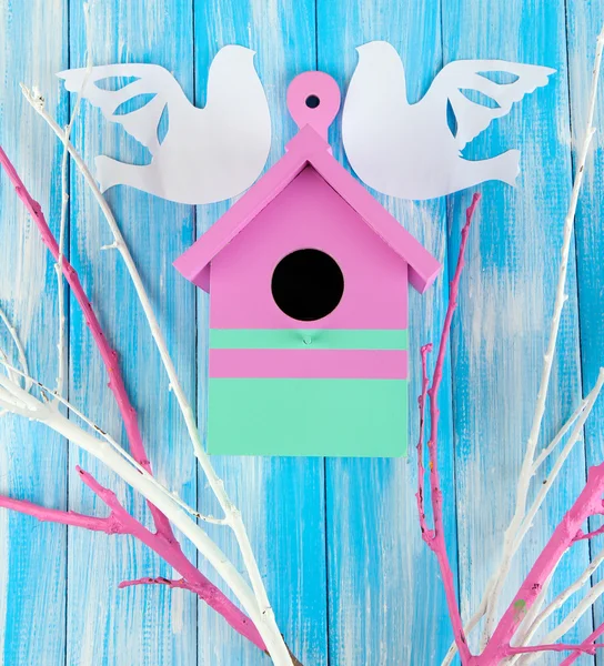 Dekoratív fészkelő doboz papír madarak és színes ágak, színes fából készült háttér — Stock Fotó