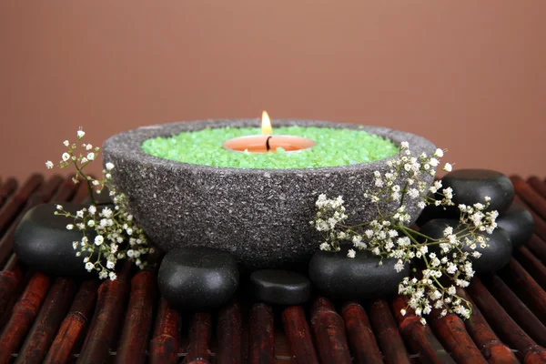 Candle in stone bowl with marine salt, on bamboo mat, on brown background — Stock Photo, Image