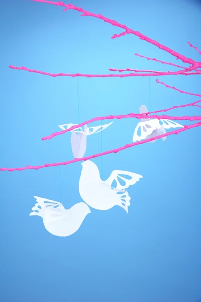 Uccelli di carta su rami rosa, su sfondo blu — Foto Stock