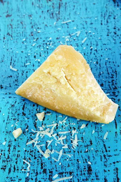 Piece of Parmesan cheese on wooden blue table close-up — Stock Photo, Image