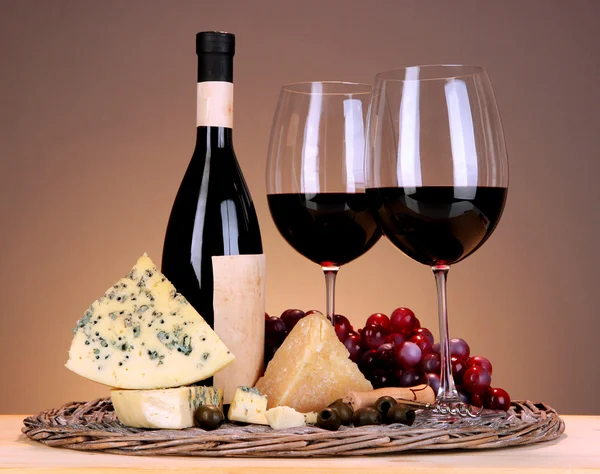 生活依然精致的红酒、 奶酪和米色背景上的木桌上的柳条托盘上的葡萄 — 图库照片