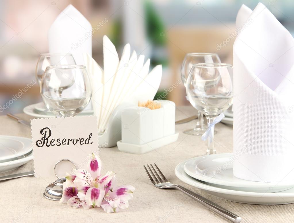 Reserved sign on restaurant table with empty dishes and glasses