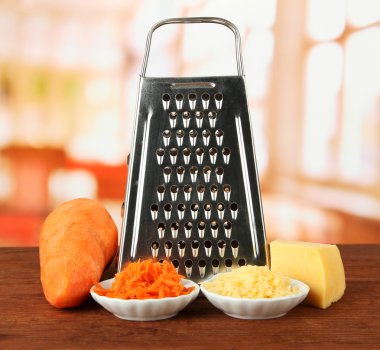 Metal grater and carrot, cheese, on bright background