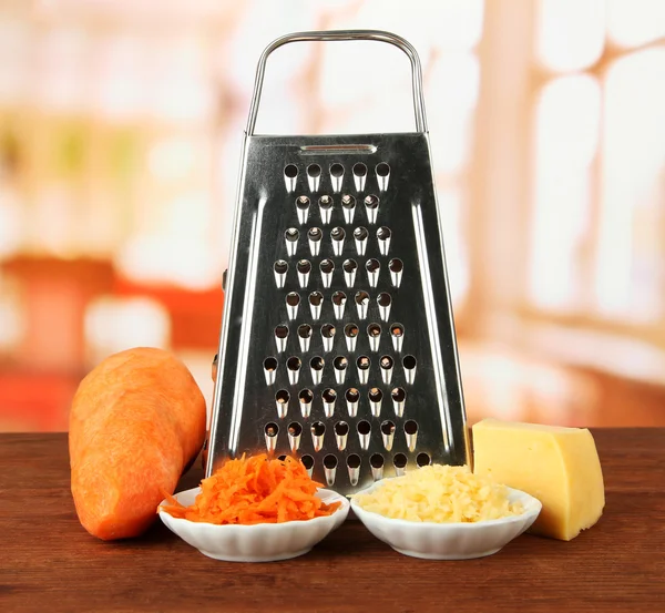 Metal grater and carrot, cheese, on bright background — Stock Photo, Image