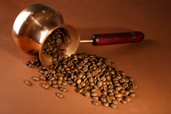Cafetera con granos de café sobre fondo marrón —  Fotos de Stock