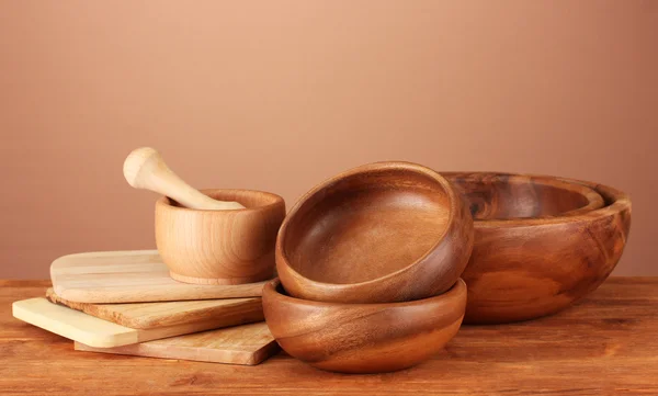 Utensílios de cozinha de madeira na mesa sobre fundo marrom — Fotografia de Stock
