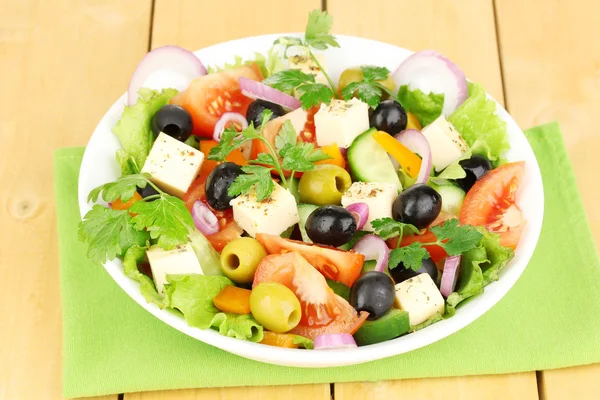 Salade fraîche dans une assiette sur une table en bois — Photo