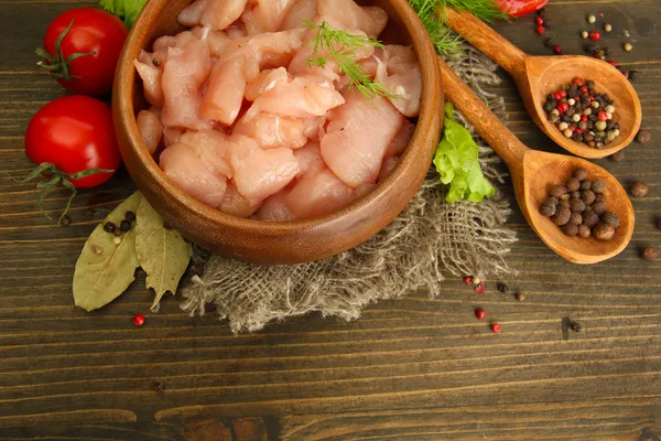 Raw chicken meat in bowl, on wooden background — Stock Photo, Image