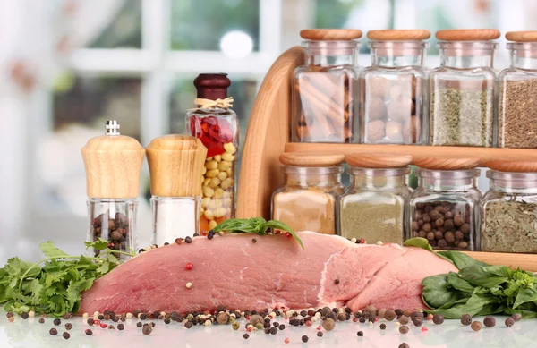 Velký kus masa, marinovaná s bylinkami a kořením na bílém stole na pozadí okna — Stock fotografie