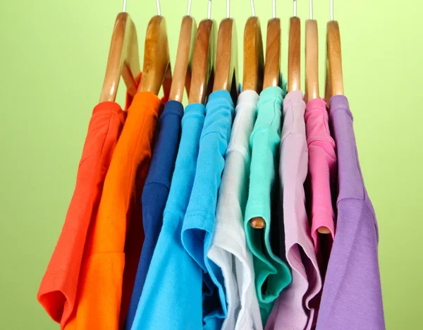 Varietà di camicie casual su appendini di legno, su sfondo blu — Foto Stock