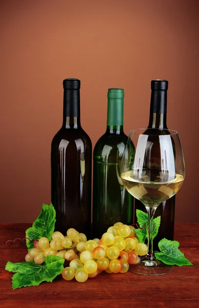 Composizione di bottiglie di vino, bicchiere di vino bianco, uva su sfondo colore — Foto Stock