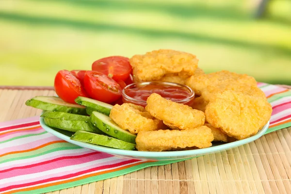 Fried chicken nuggets with vegetables and sauce on table in park — Stock Photo, Image