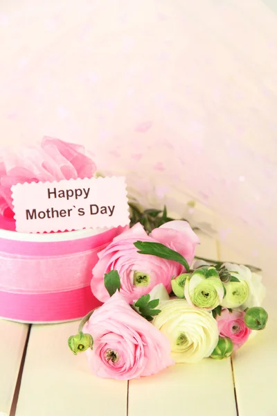 Ranunculus (buñuelos persas) y regalo para el día de las madres, sobre fondo de madera blanca — Foto de Stock