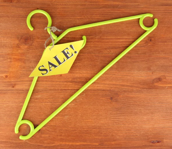 Coat hanger with sale tag on wooden background — Stock Photo, Image