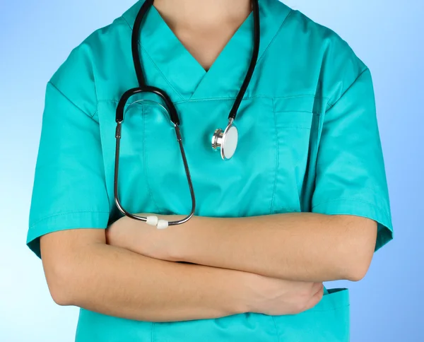 Доктор зі стетоскопом в руках на синьому фоні — стокове фото