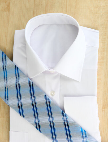 New white man's shirt with color tie on wooden background