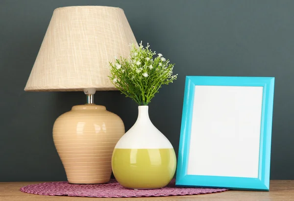 Ramki kolorowe zdjęcie, lampa i kwiaty na drewnianym stole na szarym tle — Zdjęcie stockowe