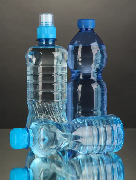 Diferentes botellas de agua sobre fondo gris —  Fotos de Stock