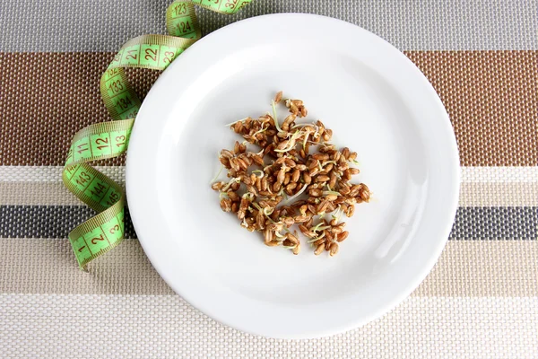 Wheat germs on plate and measuring tape, close up — Stock Photo, Image