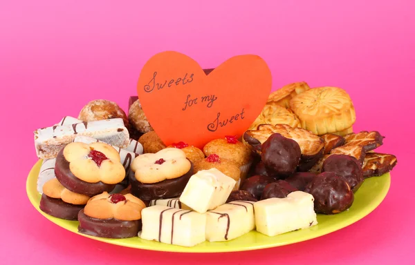 Süße Kekse auf Teller mit Valentinskarte auf rosa Hintergrund — Stockfoto