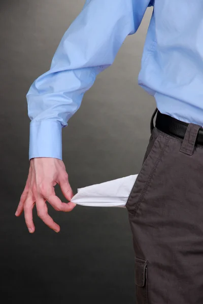 Business man showing his empty pocket, on grey background — Stock Photo, Image