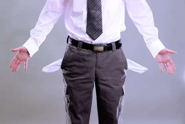 Business man showing his empty pockets, on grey background — Stock Photo, Image