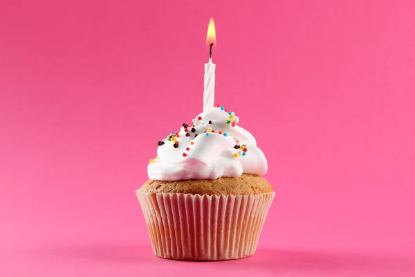 Cupcake de aniversário saboroso com vela, no fundo rosa — Fotografia de Stock