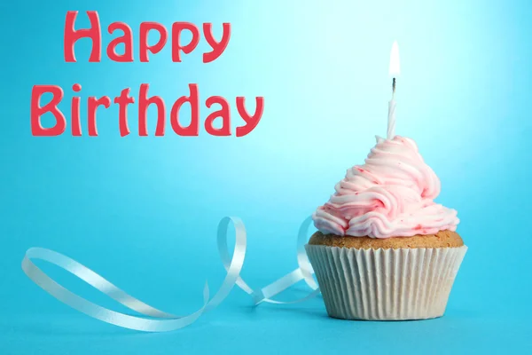 Cupcake de aniversário saboroso com vela, no fundo azul — Fotografia de Stock