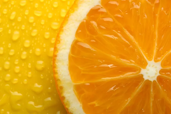 Slice of orange with drop on yellow background — Stock Photo, Image