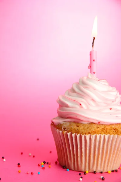 Tasty birthday cupcake with candle, on pink background Stock Picture