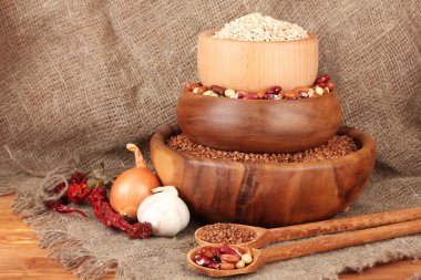 ham buğday, buğday ve fasulye masanın üstünde çul arka plan üzerinde ahşap kase